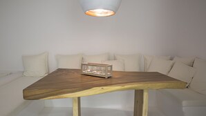 A wooden table with a glass container in the center, placed on a white sofa with matching cushions. - Villa Athena (Mykonos)