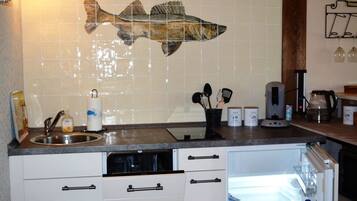 A kitchen with a fish mural, a sink, a dishwasher, and a refrigerator.