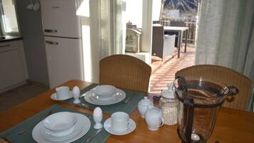A dining area with a table set for four, including plates, cups, and cutlery. A coffee pot and a candle are also visible.
