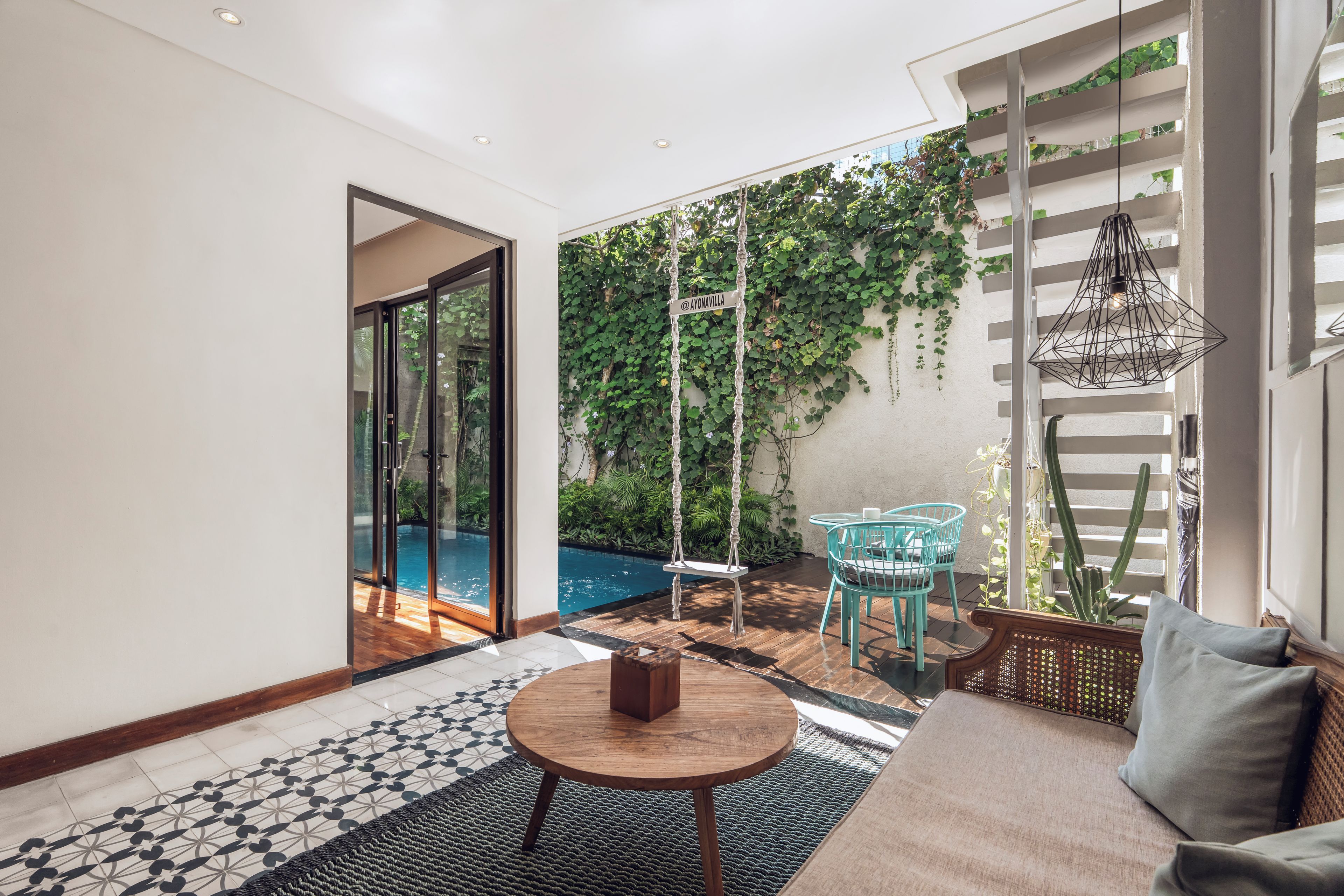 A modern living room with a pool, a swing, and a view of greenery.