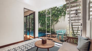 A modern living room with a pool, a swing, and a view of greenery.