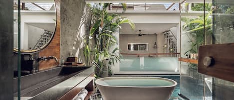 A modern bathroom with a freestanding bathtub, a wooden vanity, and a glass-enclosed shower area.