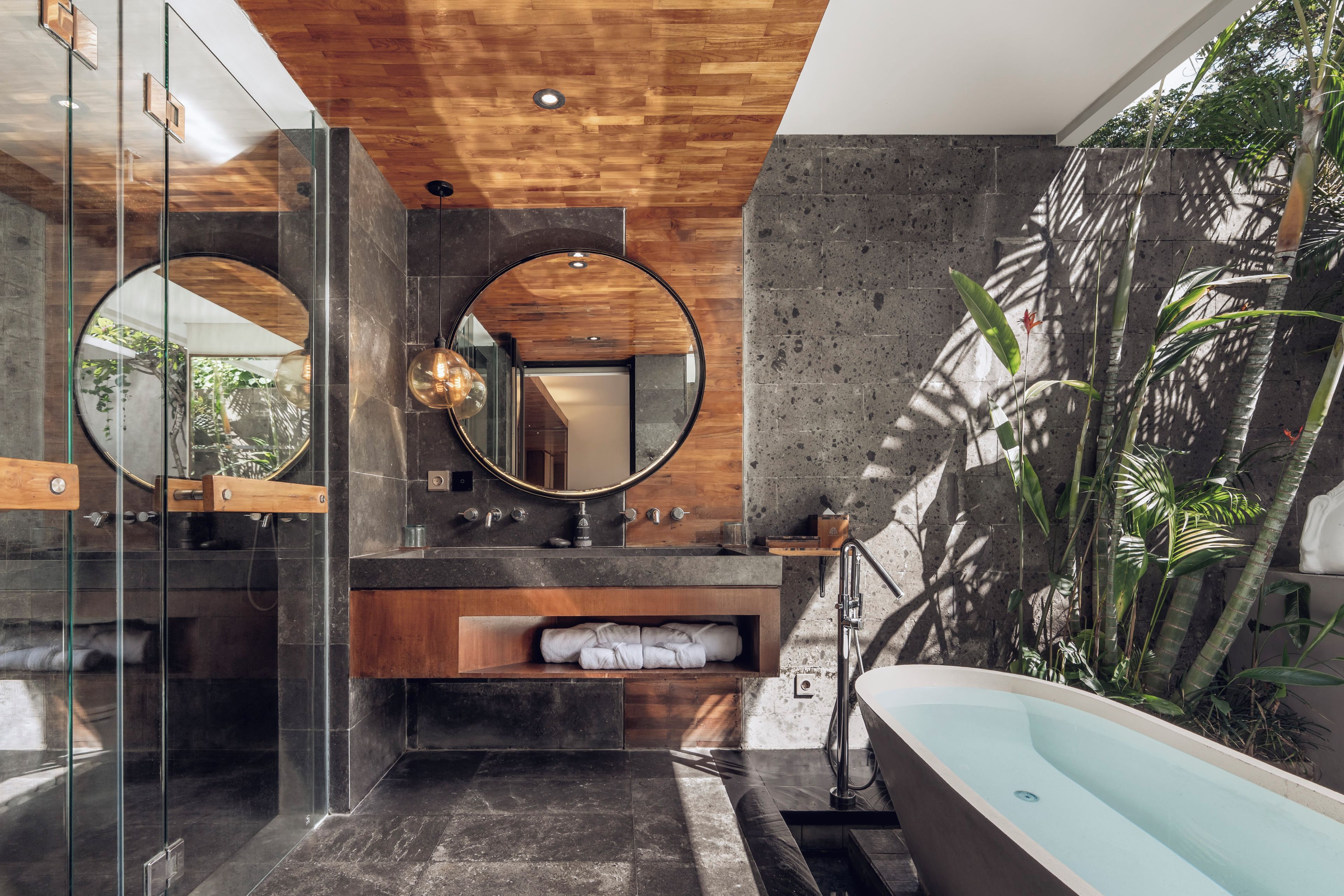 Une salle de bain moderne avec une douche à parois de verre, une baignoire sur pieds et un grand miroir.