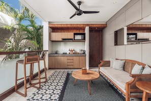 A modern kitchen with wooden cabinets, a ceiling fan, and a dining area with a round table and chairs. - Ayona Villa Seminyak by Ini Vie Hospitality (Kerobokan)