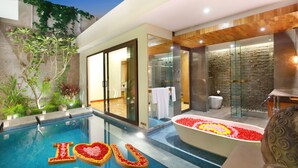 Interior moderno de hotel con piscina, zona de spa y una bañera grande con arreglos florales.