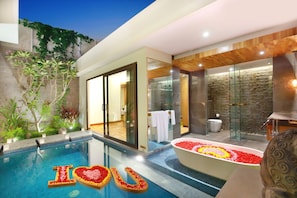 A modern hotel interior with a swimming pool, a spa area, and a large bathtub with flower arrangements. - Ayona Villa Seminyak by Ini Vie Hospitality (Kerobokan)