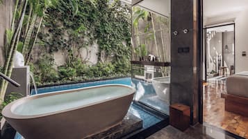 A modern bathroom with a freestanding bathtub, a glass-enclosed shower area, and a wall covered with greenery.