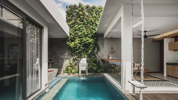 Una piscina interior moderna con pared verde y una hamaca colgante.