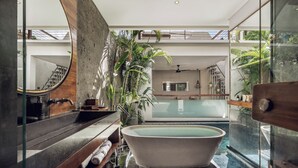 A modern bathroom with a freestanding bathtub, a wooden vanity, and a glass-enclosed shower area.