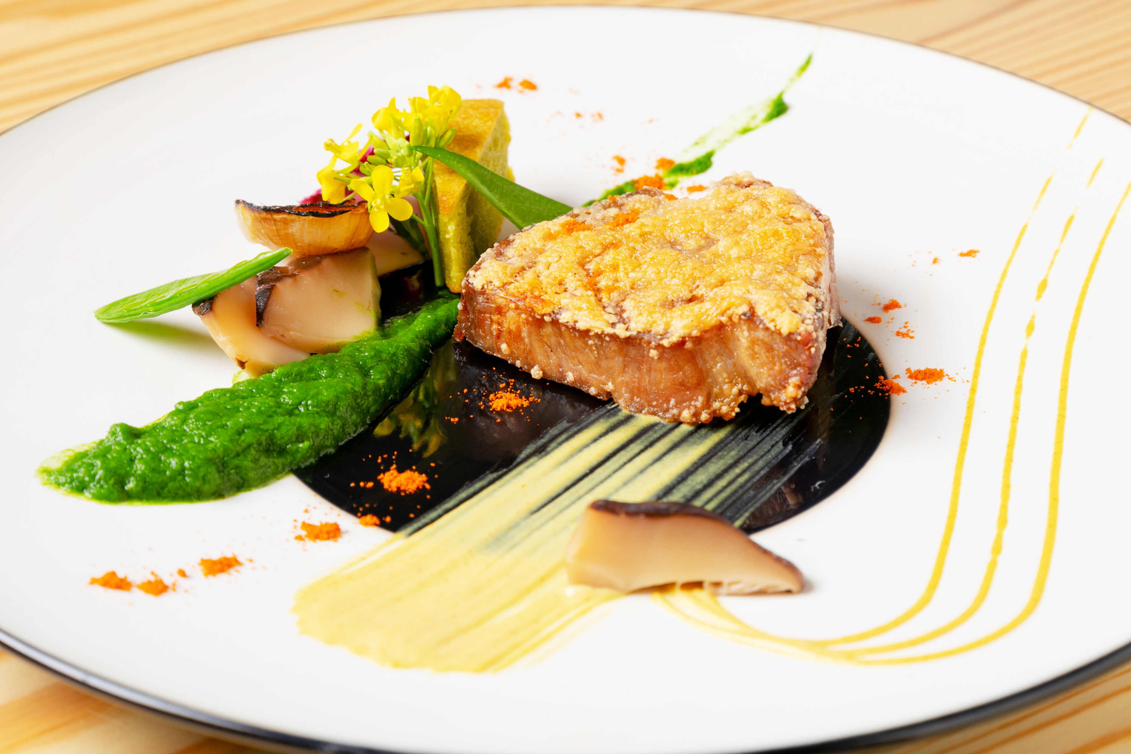 A plate of food with a piece of breaded meat, vegetables, and a sauce.