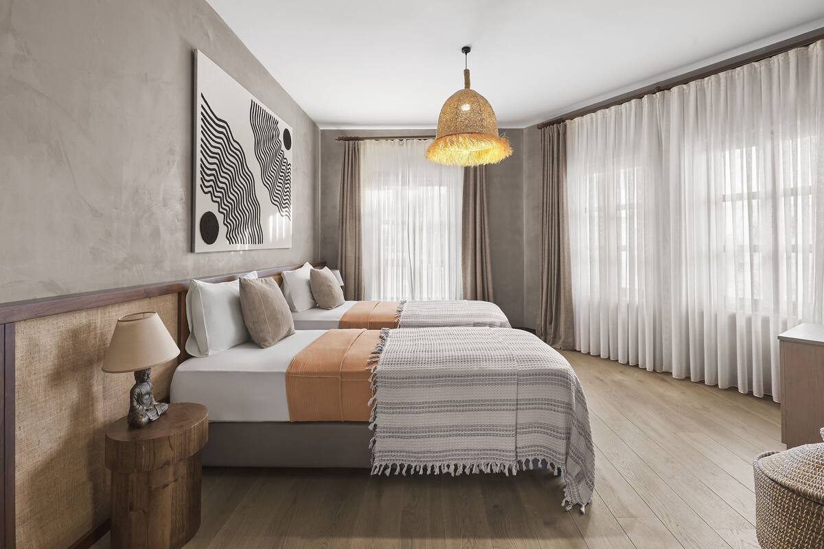 Un dormitorio moderno con una cama grande, una lámpara colgante y vistas al exterior a través de cortinas traslúcidas.