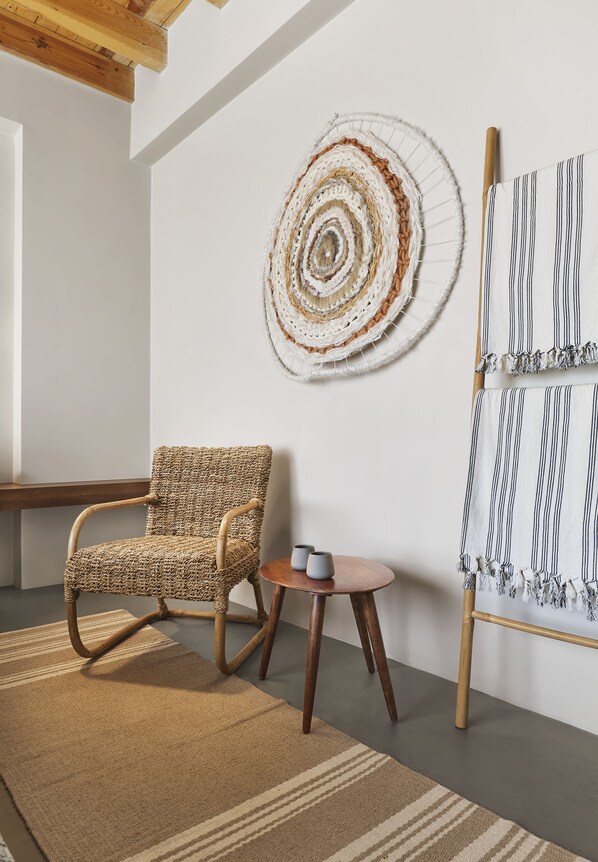 A room with a woven chair, a round wall art piece, and a striped fabric on a stand. - Kaipo Alacati (Cesme)