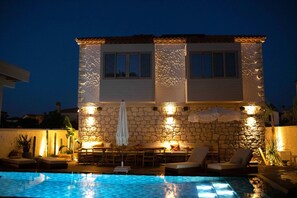 A stone building with a pool, outdoor seating, and a table with umbrellas. - Kaipo Alacati (Cesme)