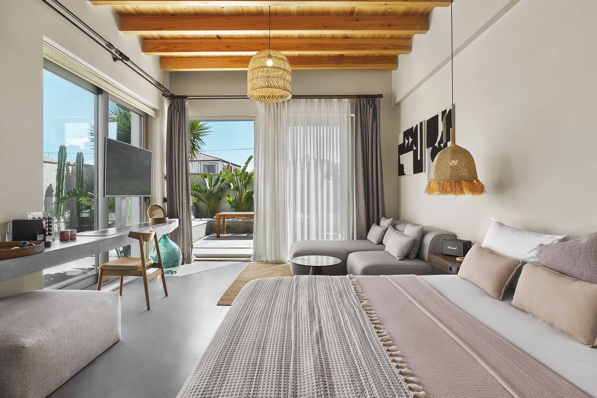 Un dormitorio moderno con una cama grande, un sofá y una zona de escritorio.