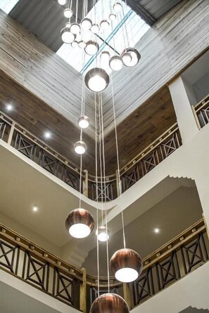 A multi-level interior with a central hanging light fixture and wooden beams. - Udaan Olive Hotel & Spa Pelling (Gyalshing)