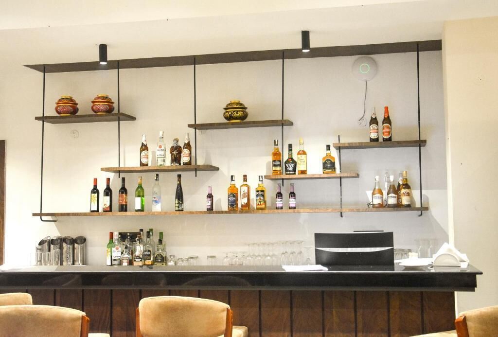 A bar area with shelves of liquor bottles, glasses, and a bar counter.