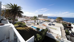 A residential area with a swimming pool, palm trees, and a view of the sea. - Refurbished 1-bed in popular Los Gigantes w/large terrace, sea & cliff views (Los Gigantes)