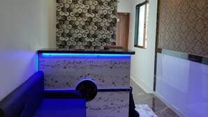 A modern reception area with a patterned wall, a marble counter, and a blue-lit seating area. - Hotel Aiston Inn (Mumbai)
