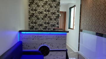 A modern reception area with a patterned wall, a marble counter, and a blue-lit seating area.
