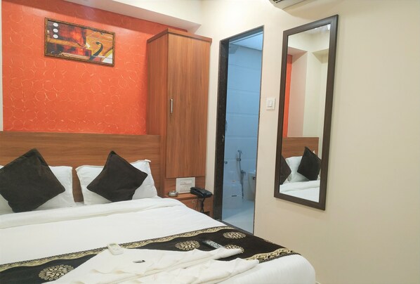A hotel room with a bed, a wardrobe, a mirror, and a shower area. - Hotel Aiston Inn (Mumbai)