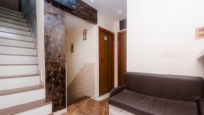 A reception area with a marble staircase, a brown sofa, and wooden doors. - Hotel Aiston Inn (Mumbai)