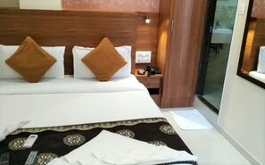 A hotel room with a bed, a bedside table with a phone, and a window. - Hotel Aiston Inn (Mumbai)