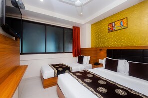 A hotel room with two beds, a television, a ceiling fan, and a large window with curtains. - Hotel Aiston Inn (Mumbai)