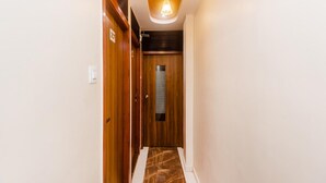 A hallway with wooden doors, a marble floor, and a ceiling light fixture. - Hotel Aiston Inn (Mumbai)