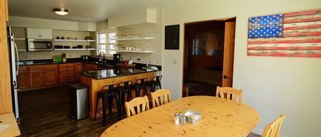 Una cocina moderna con armarios de madera, una isla central y un comedor con mesa y sillas de madera.