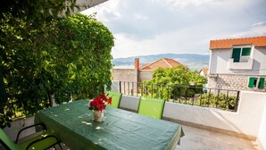 An outdoor patio with a table set for two, surrounded by greenery and a view of the countryside. - Villa with sea view and swimming pool (Trogir)