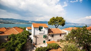 A coastal village with stone buildings and red-tiled roofs, surrounded by greenery and a clear view of the sea and mountains. - Villa with sea view and swimming pool (Trogir)