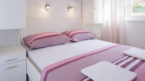 A bedroom with a bed, bedside tables, a wardrobe, and a window with curtains. - Villa with sea view and swimming pool (Trogir)