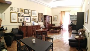 A spacious living room with a dining area, a kitchen in the background, and a dining table with chairs. - B&B Lumasa (Vietri sul Mare)