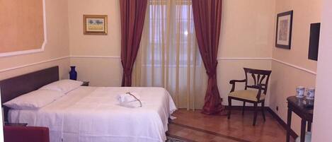 A hotel room with a bed, a chair, a small table, and a rug.