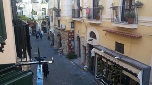 A narrow street with buildings on either side, a visible storefront with a sign, and a few pedestrians. - B&B Lumasa (Vietri sul Mare)