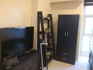 Cozy living space with a flat-screen TV, shelving unit, and wardrobe.
