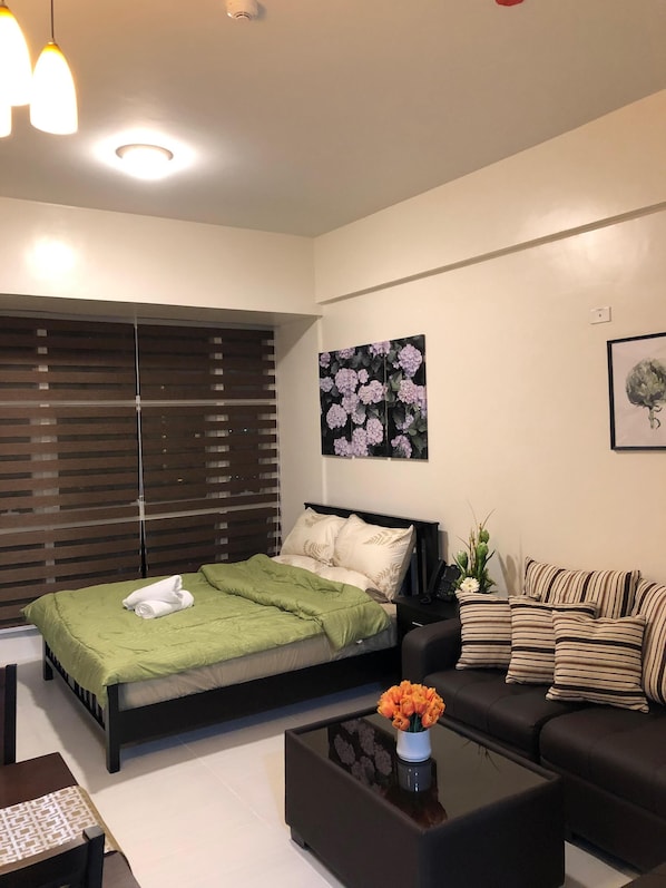 Relax in a serene bedroom with a large bed, sofa, and a beautiful floral artwork.