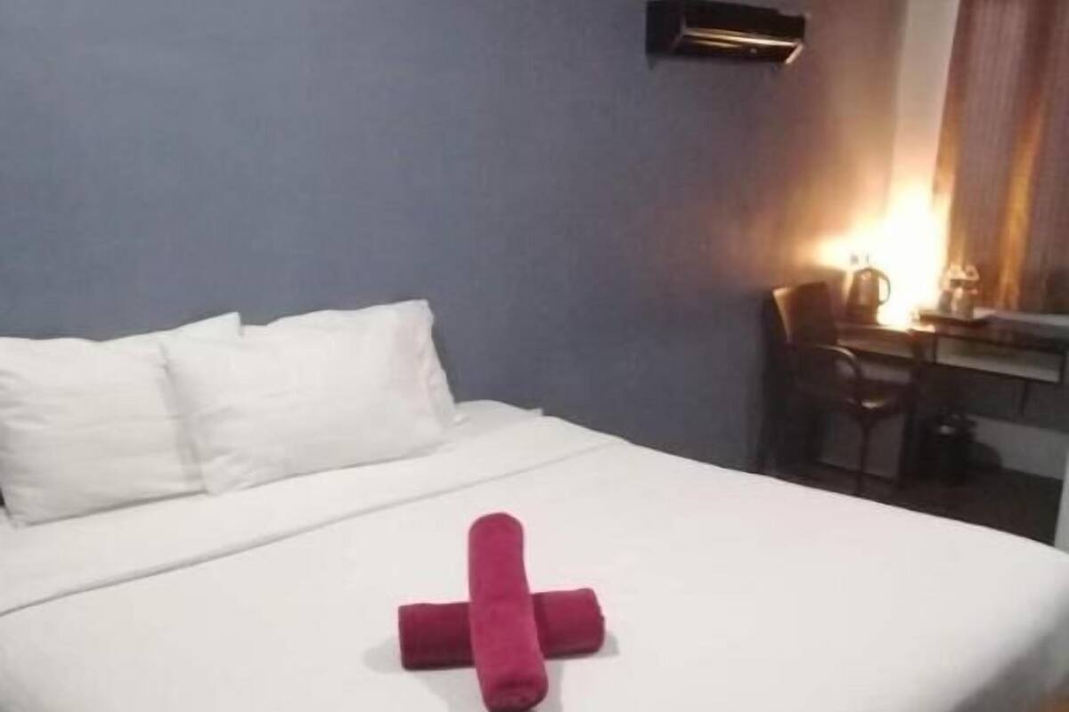 A hotel room with a bed, a desk, and a chair.
