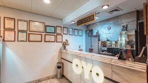A reception area with a marble counter, framed certificates on the wall, and a reception desk. - OYO 671 Hotel Capitol (Jakarta)