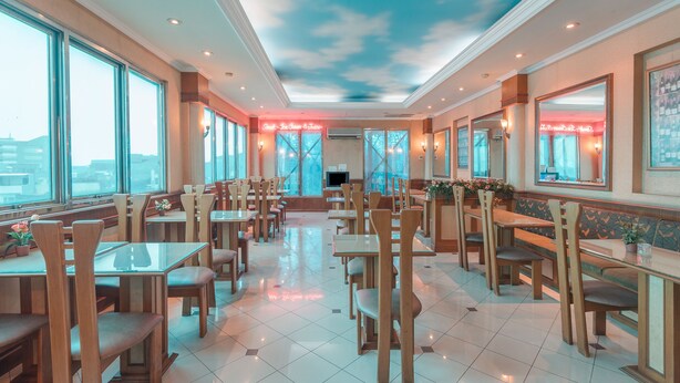 A spacious restaurant with high ceilings, large windows, and a modern interior design. - OYO 671 Hotel Capitol (Jakarta)
