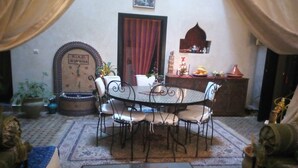 A dining area with a round table and chairs, a clock on the wall, and a decorative cabinet. - Riad Zinnha (Marrakech)