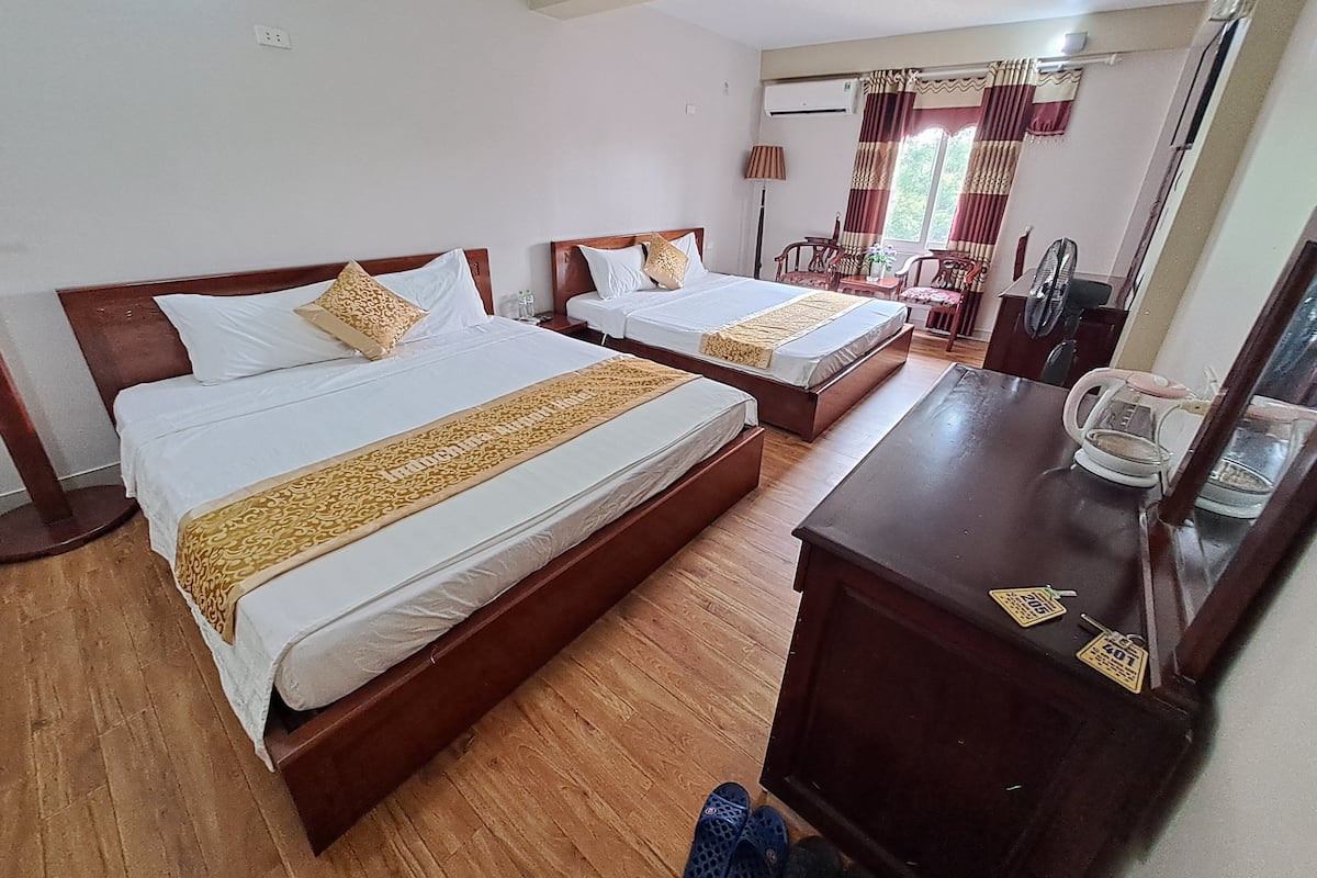 Ein Hotelzimmer mit zwei Betten, einem Holzkapfen, einem Schreibtisch und einem Sessel.