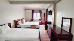 Habitación de hotel con dos camas, un televisor, un escritorio y una silla.
