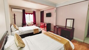 Une chambre d’hôtel avec deux lits, un bureau, une commode et un téléviseur.
