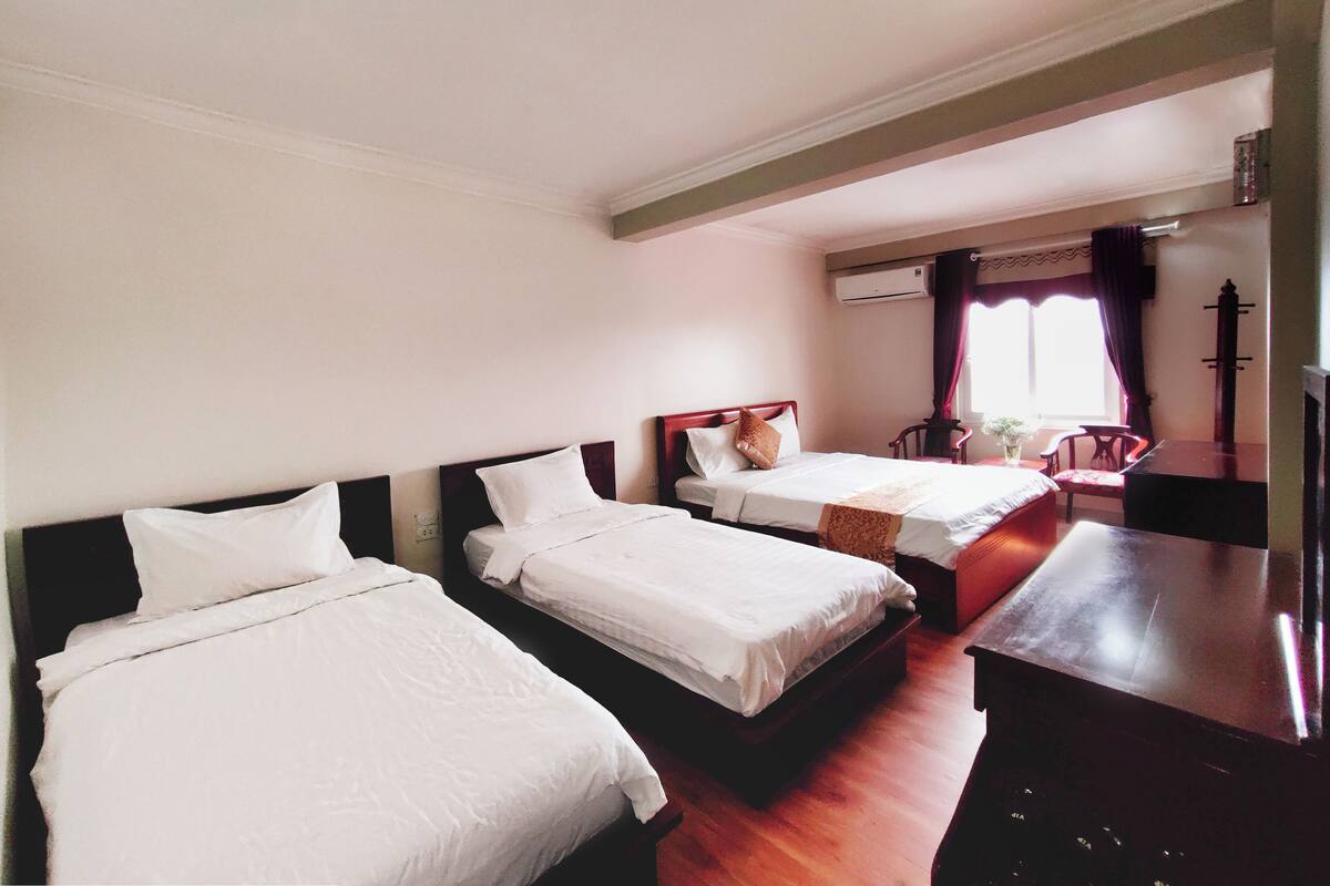 Ein Hotelzimmer mit zwei Betten, einem Holztisch und einem Stuhl.