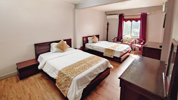 Une chambre d’hôtel avec deux lits, un plancher en bois, un bureau et une chaise.
