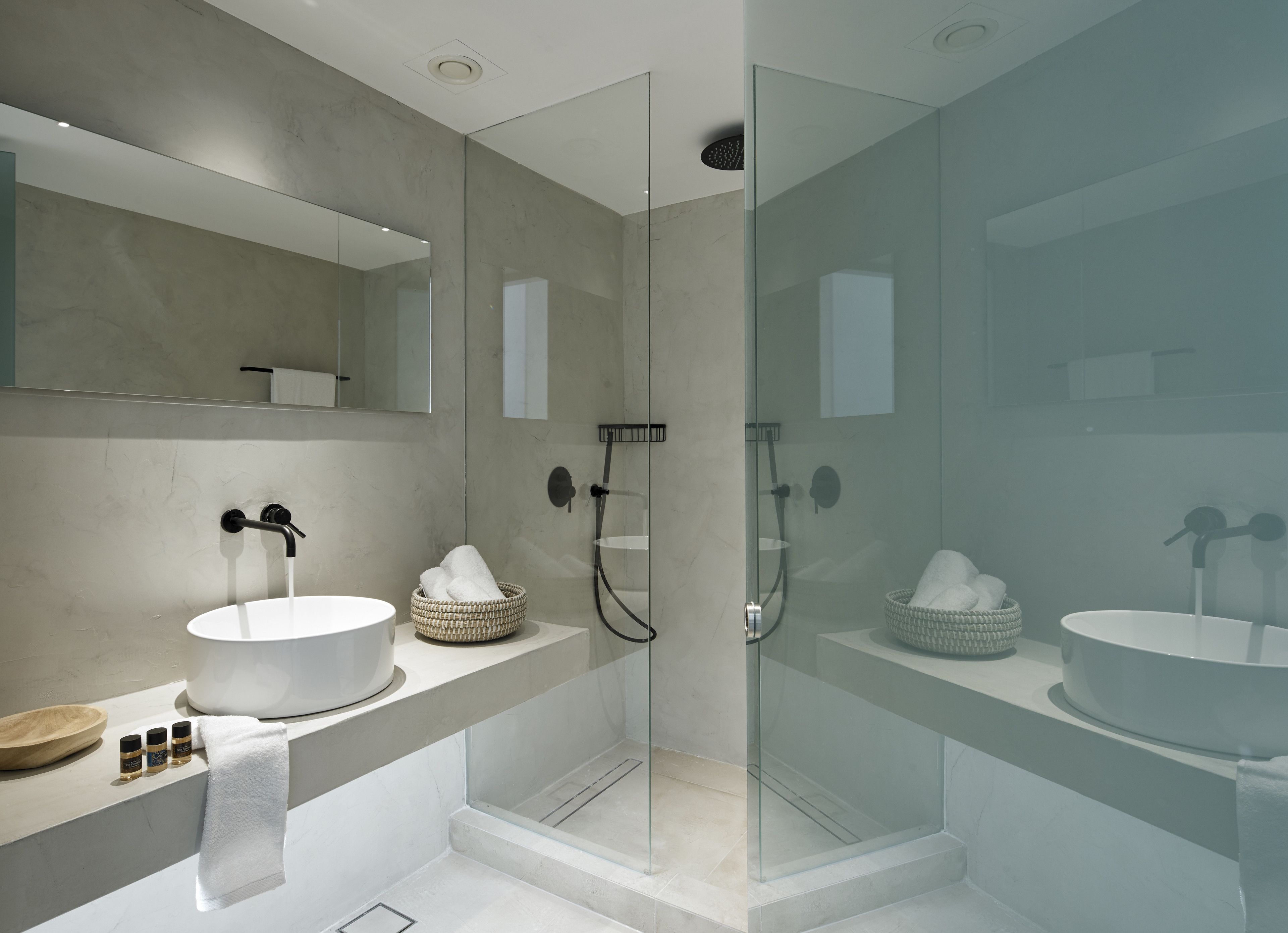 Un baño moderno con dos lavamanos, cabina de ducha de vidrio y un espejo grande.