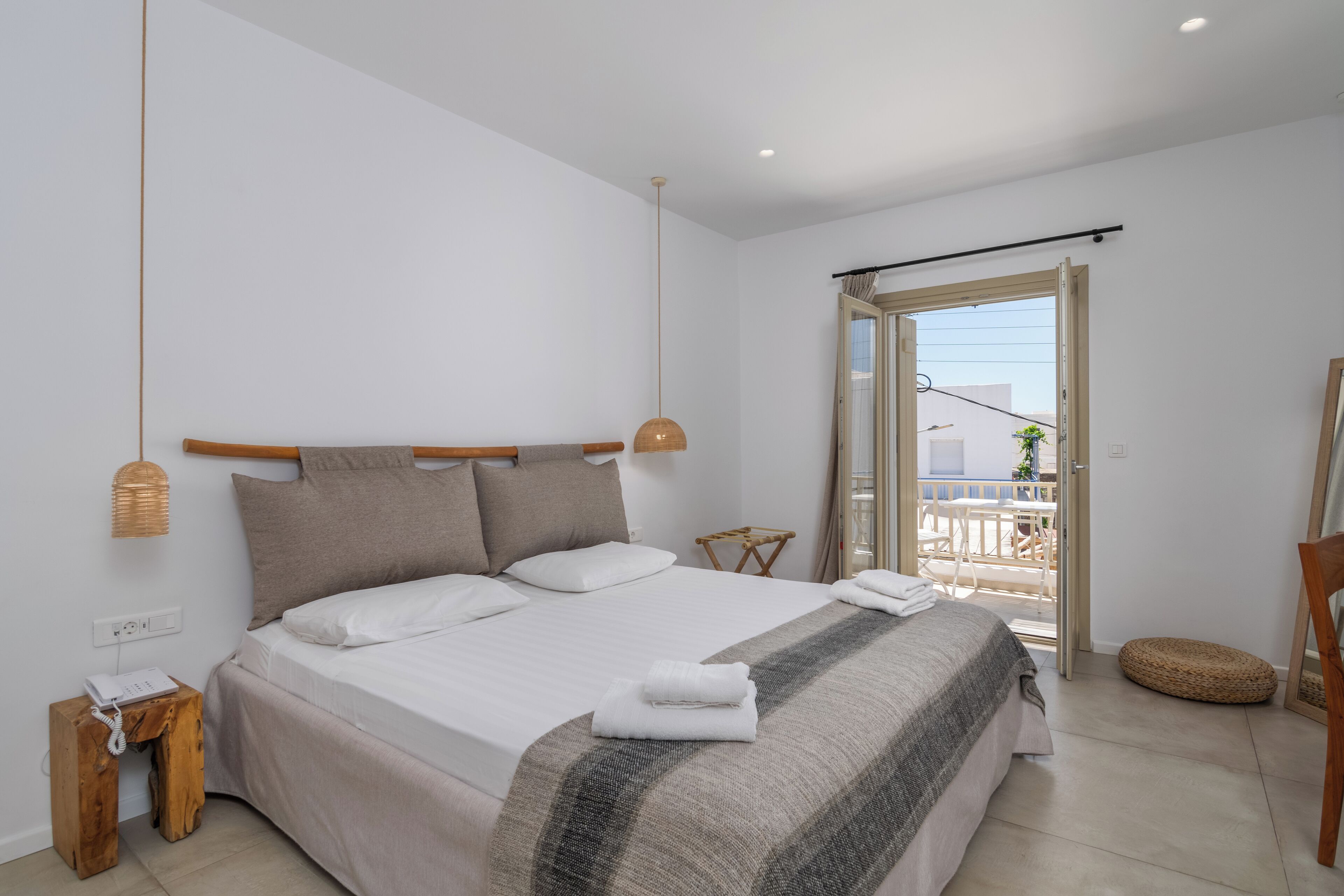 A bedroom with a bed, a bedside table, a lamp, a window, and a balcony.