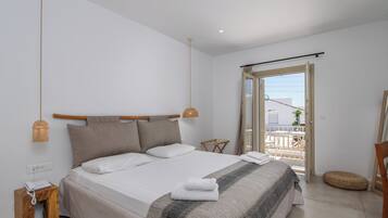 A bedroom with a bed, a bedside table, a lamp, a window, and a balcony.