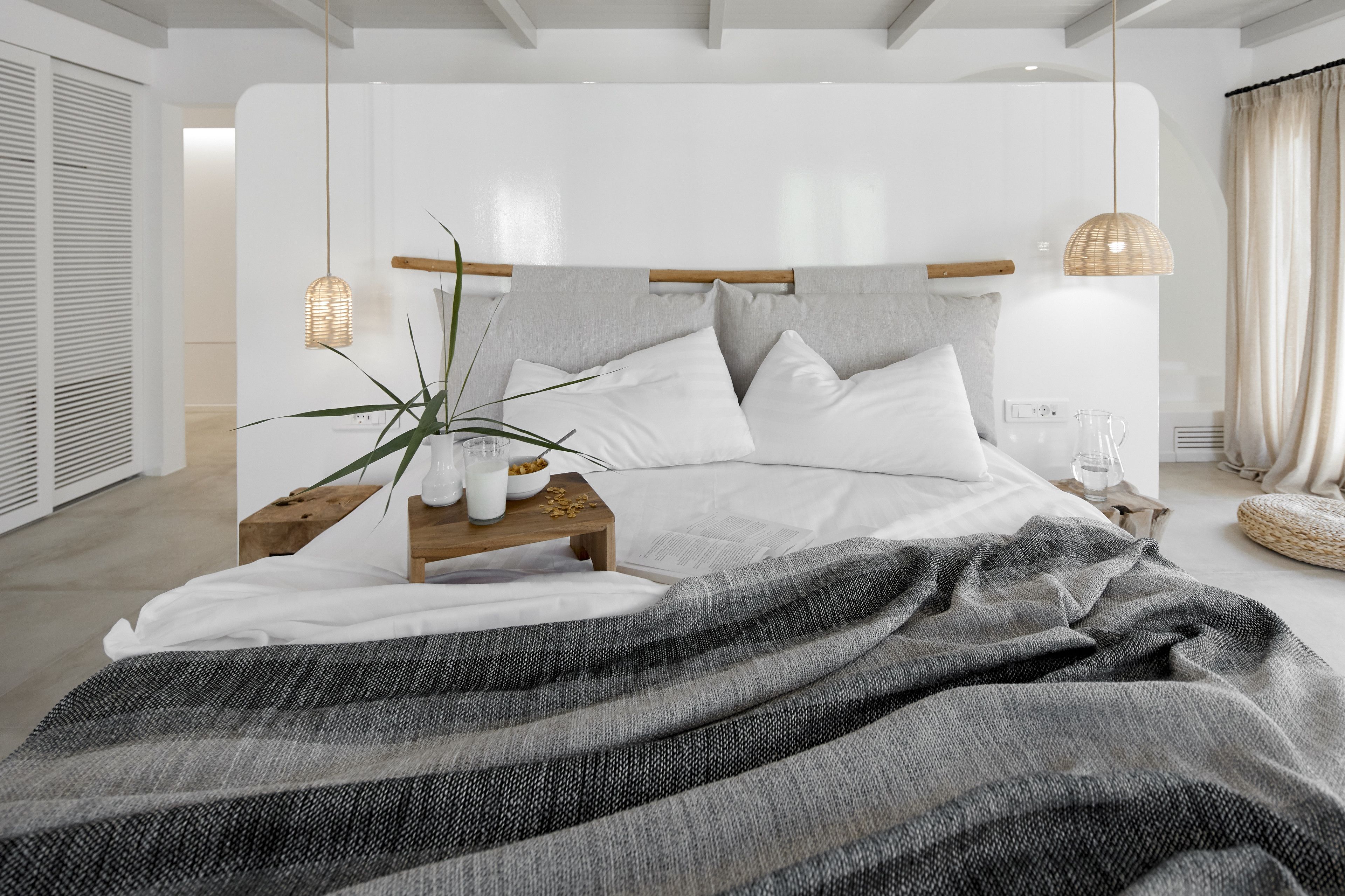 Un dormitorio moderno con una cama grande, mesitas de noche, una lámpara colgante y una planta en maceta.